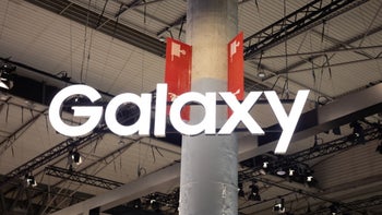 The Galaxy logo in white is posted on a column inside a building hosting a trade show.