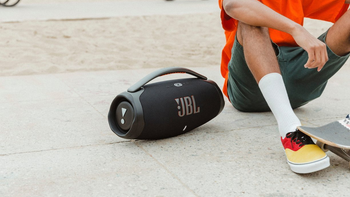 JBL Boombox 3 placed on a concrete surface next to a person wearing shorts.