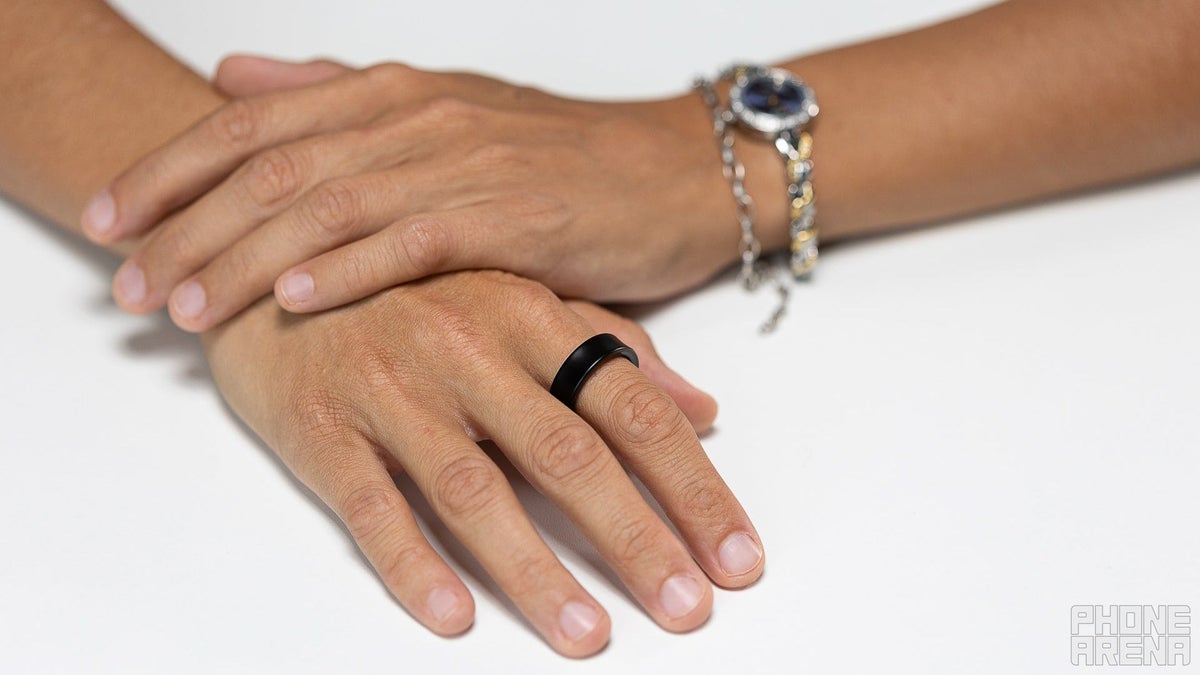 A person's hands with the Galaxy Ring on the index finger on a white table.