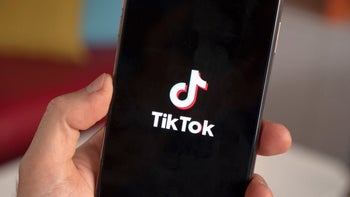 A person holding a smartphone displaying the TikTok app.