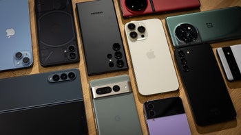 A collection of various smartphones arranged on a wooden surface.