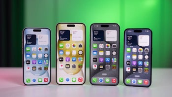 Several iPhones on a desk on a green background.