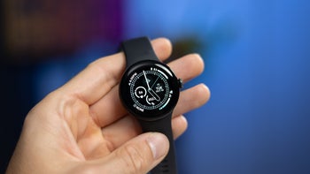 A person's hand holding the Pixel Watch 2 with a sleek black band, showcasing its minimalist round display.