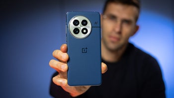 A person holding the OnePlus 13 smartphone in blue.