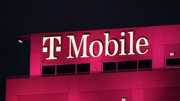 A building at night shows off the T-Mobile name in white, under lights.