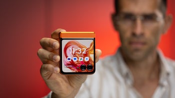 A man holds a folded Motorola Razr (2024), showing its cover screen with app icons and a dual-camera setup.