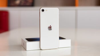 A white iPhone SE 3 standing on a desk.