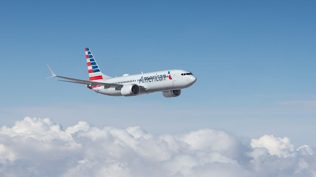 An American Airlines jet is shown flying above the clouds on a nice sunny day.