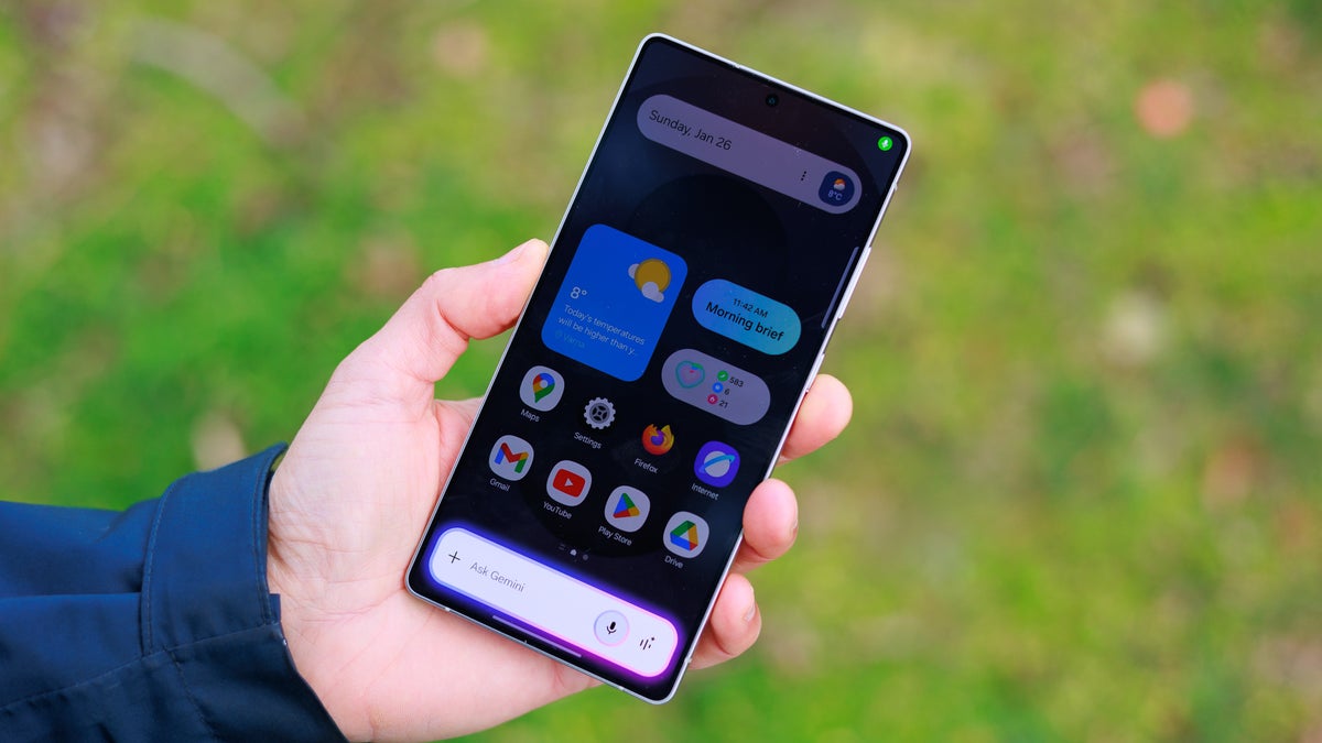 Hand holding phone with activated assistant.