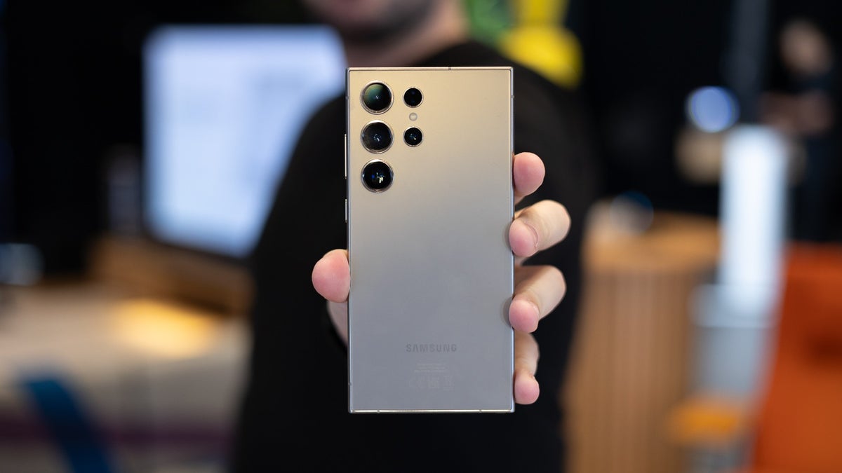 A Galaxy S24 Ultra model being held by a person who showcases the phone's rear design and quadruple camera system.
