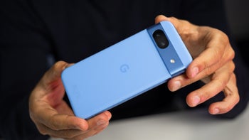 A person holds the Pixel 8a, showcasing the phone's rear design and camera module.