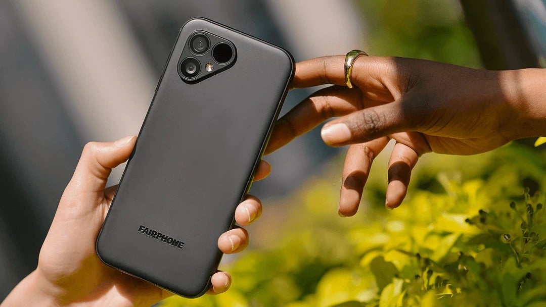 Marketing image of the Fairphone in a user's hands passing it to another