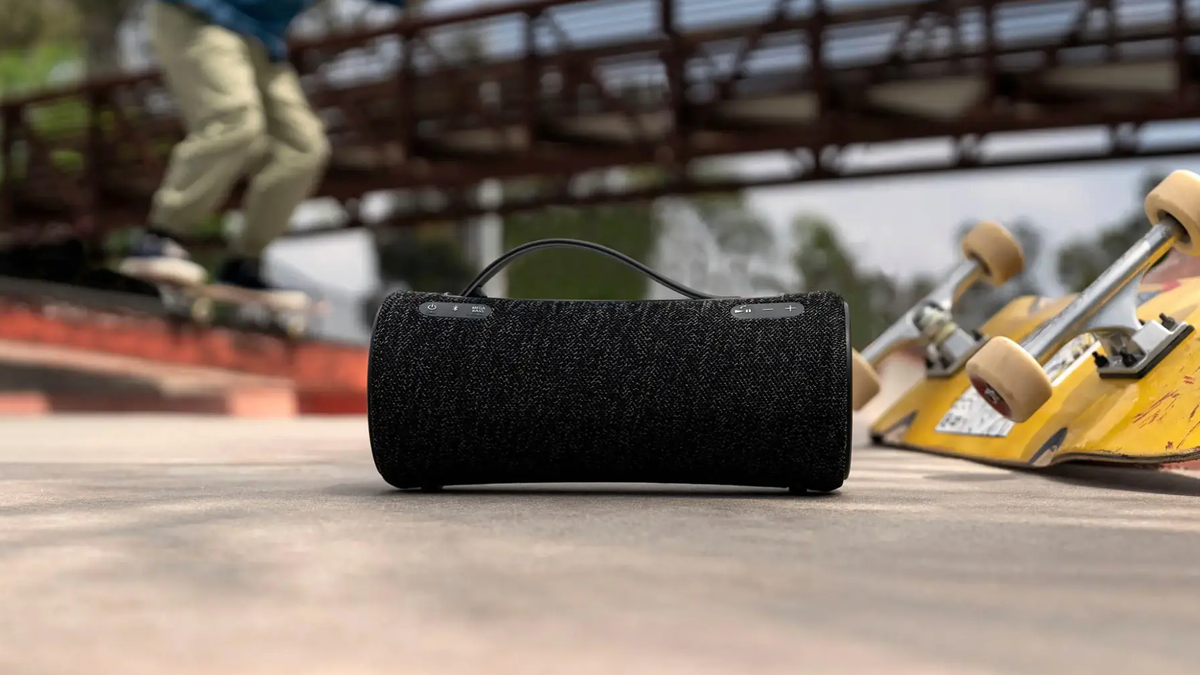 Sony SRS-XG300 speaker is placed by a skateboard in an outdoor setting.