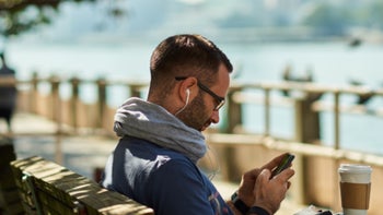 A man in New York City is using his cellphone while drinking coffee.