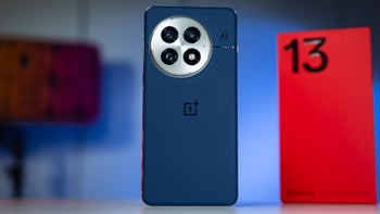 OnePlus 13 handset showcases its rear camera module, with its retail box visible in the background.