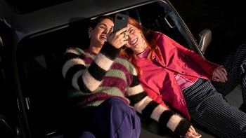 Two women holding the new Pixel 9a and looking at it, smiling.