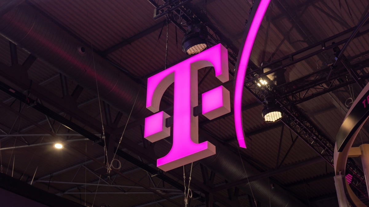 Image showing the T-Mobile logo, a magenta "T", suspended from a ceiling in an indoor setting.