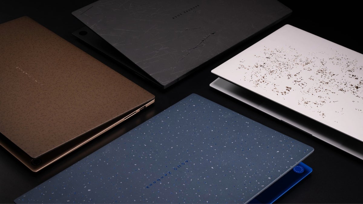 Four closed ASUS Zenbook laptops in different colors on a dark surface.