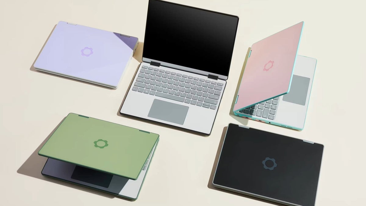Five Framework laptops in different colors arranged on a light surface.