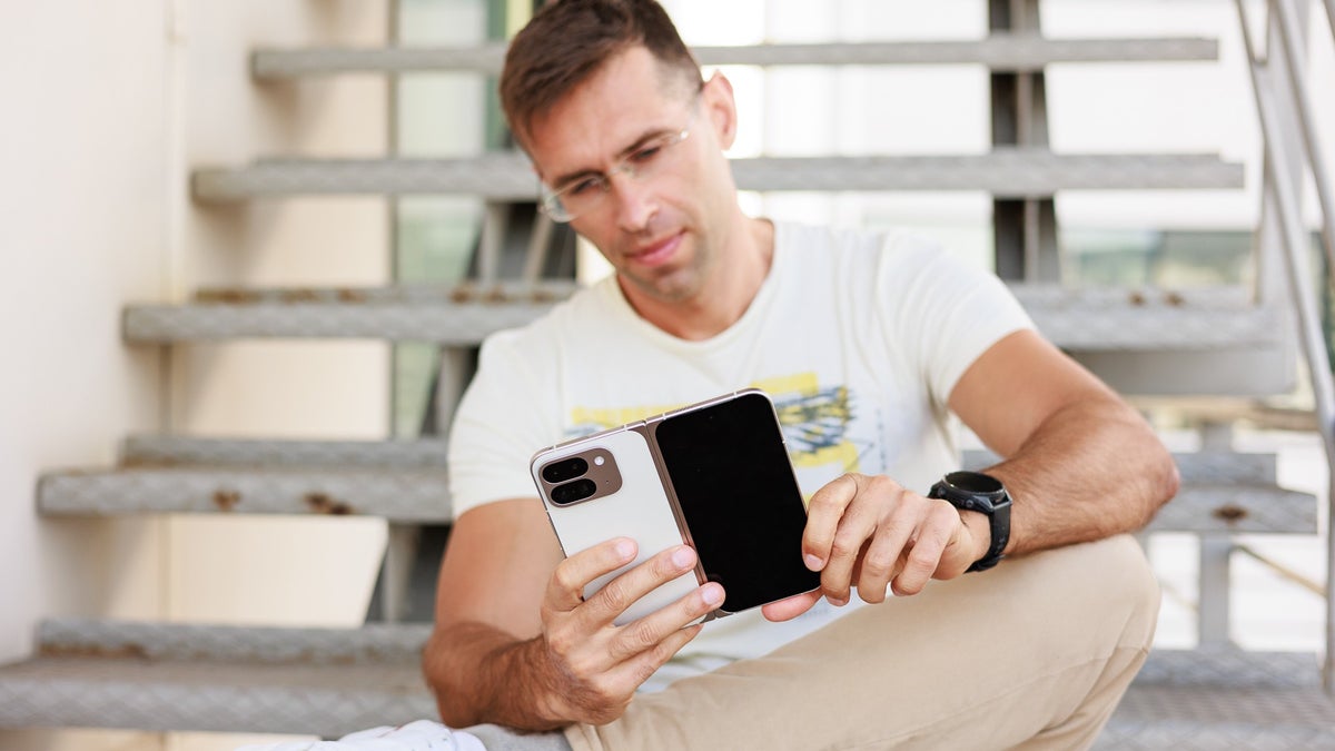 A person sitting on stairs interacts with the Google Pixel 9 Pro Fold, looking at its main display.