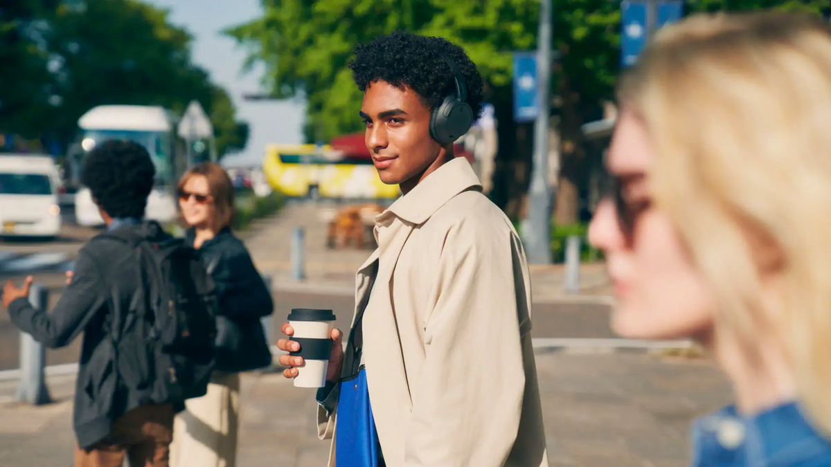 A person wears the Sony WH-CH720N in an outdoor setting.