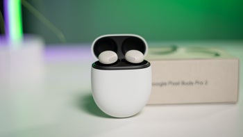 Pixel Buds Pro 2 are placed in their charging case on a white table against a green background.