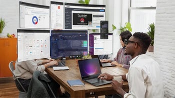 People collaborating with multiple computer screens.