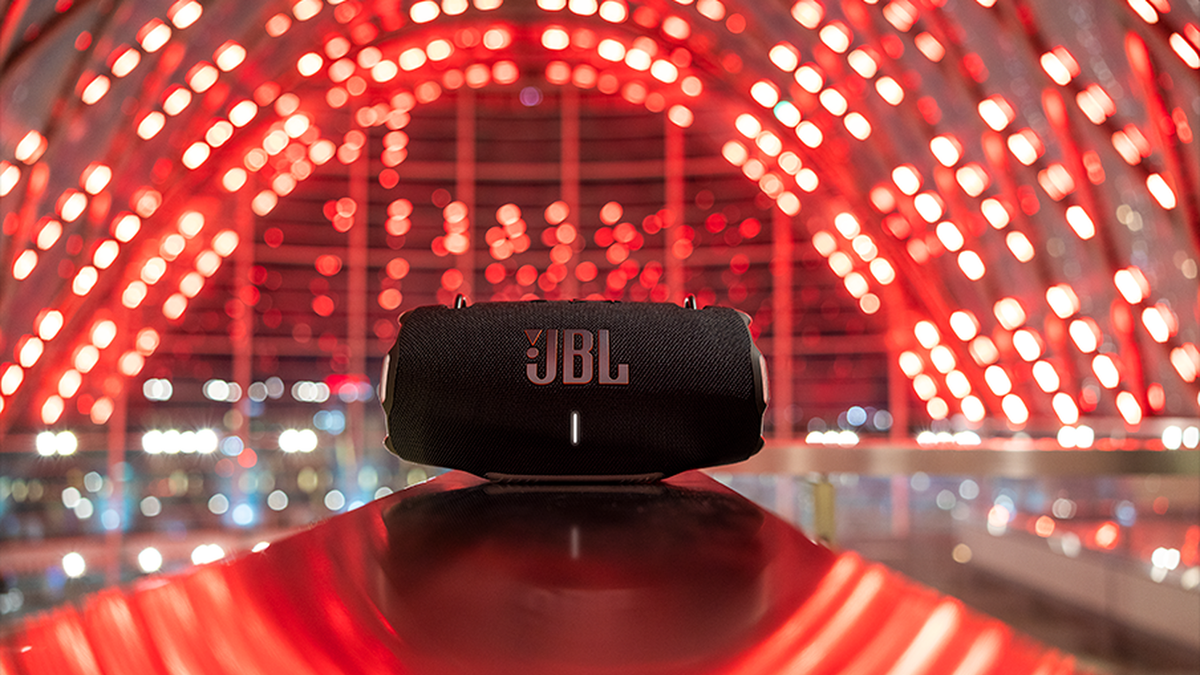 JBL Xtreme 4 speaker placed on a reflective surface is surrounded by red lights.