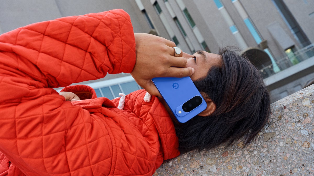 A person holding the Pixel 10 in Indigo while talking on the phone, showing off the vibrant color in a casual, urban setting.