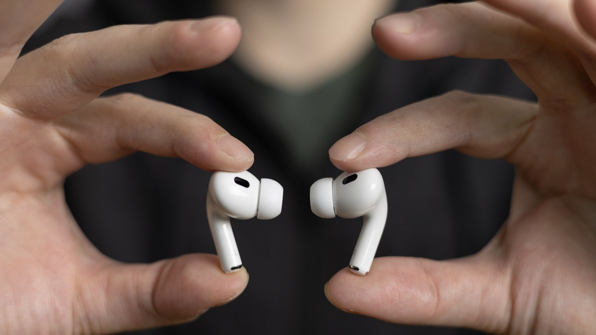 A person holds the AirPods Pro 2 with their index finger and thumb, highlighting their compact design.