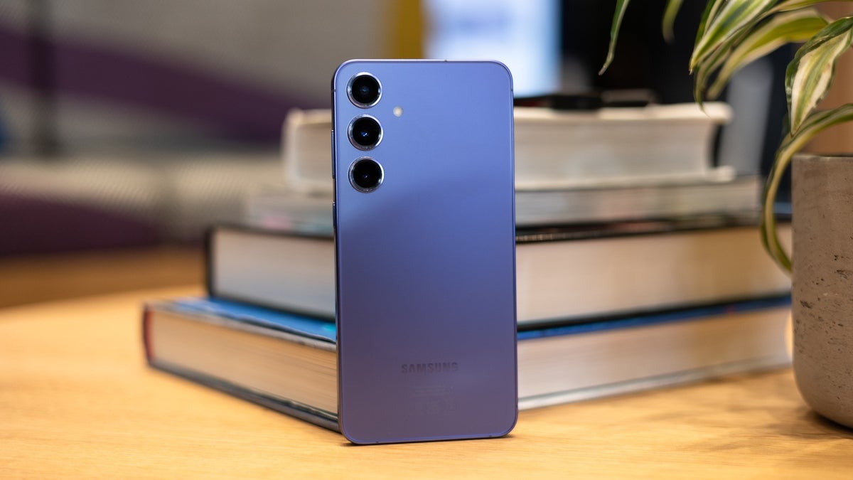 Galaxy S24+ on a wooden table with books seen in the background.