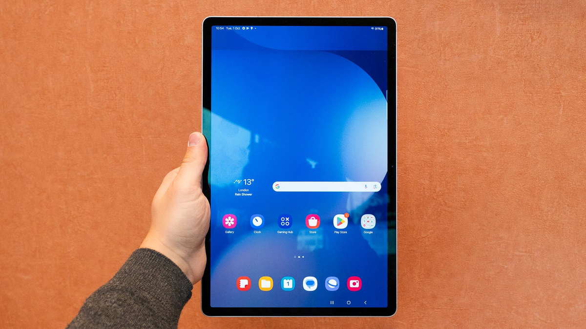 A person holds the Galaxy Tab S10+ against an orange background, highlighting its display.