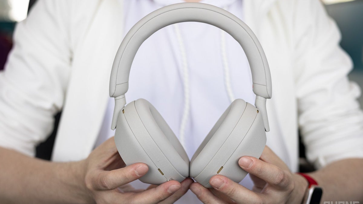 A person holding a pair of Sony WH-1000XM5.