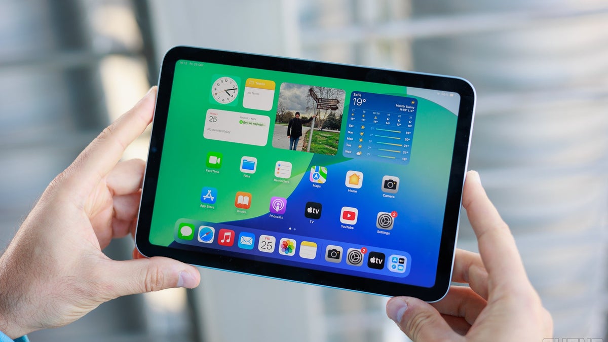 A close-up of two hands holding an iPad Mini 7.