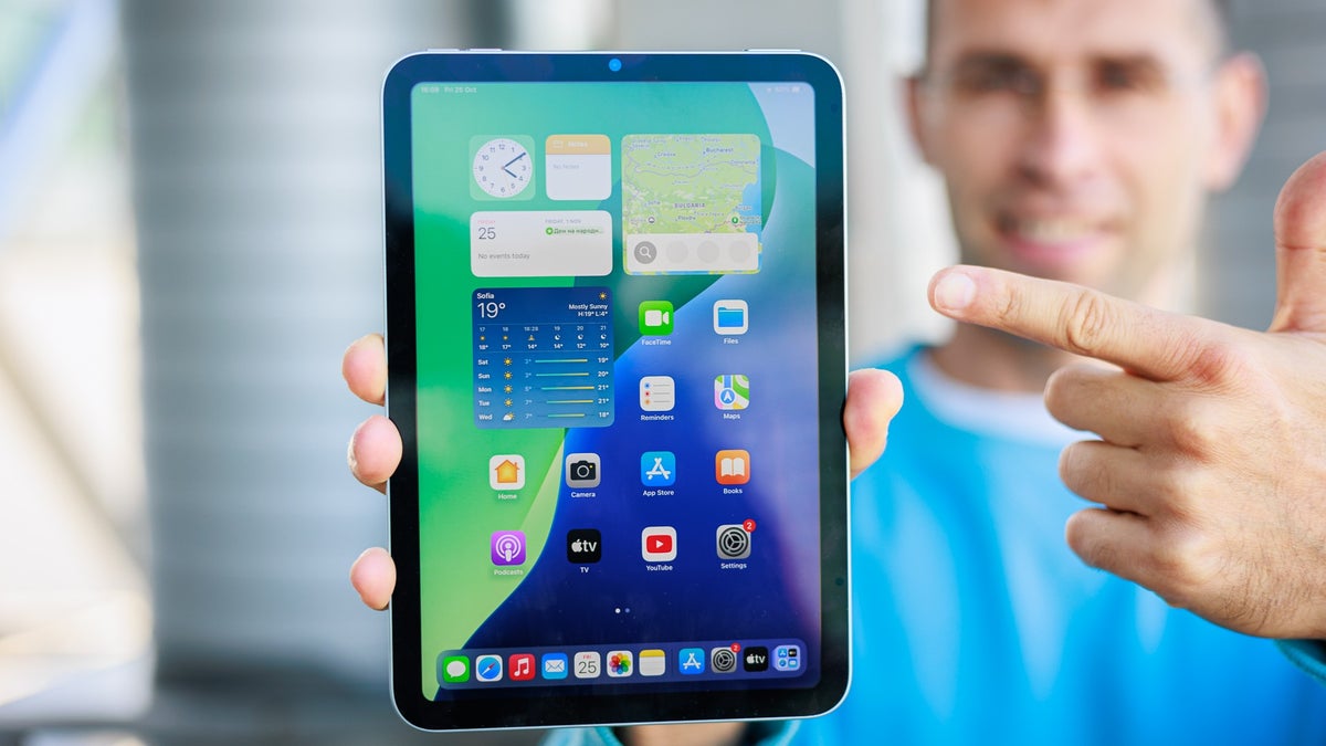A person holds the iPad mini (A17 Pro), pointing at its compact display.