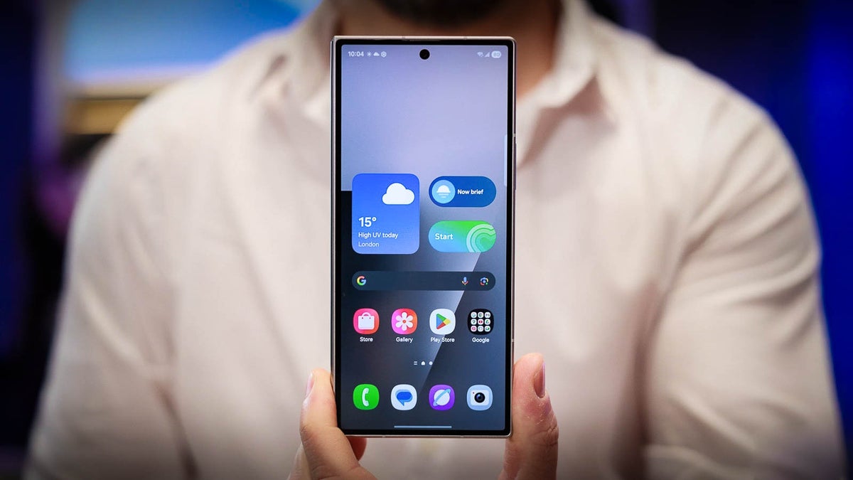 Person holding a Samsung Galaxy Z Fold 7 in phone mode, showing its home screen with weather and app widgets.