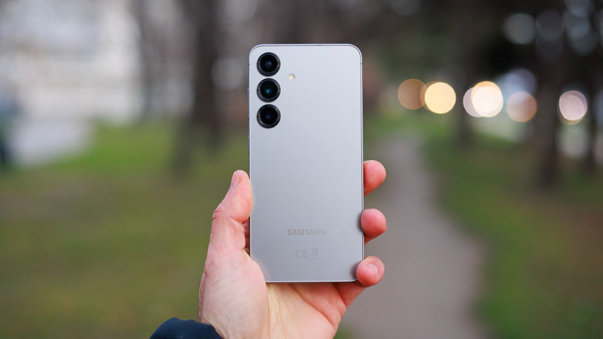 Holding up the Samsung Galaxy S25 in a park