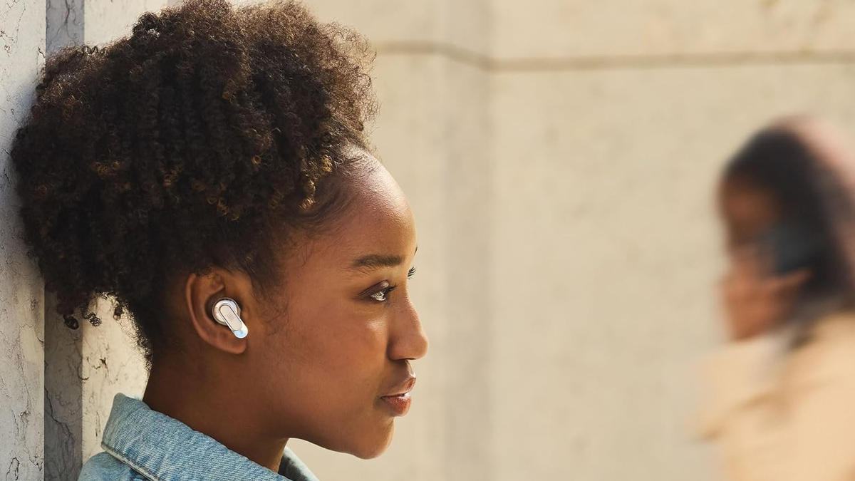 A profile of a woman wearing the JBL Tour Pro 3 in an outdoor setting.