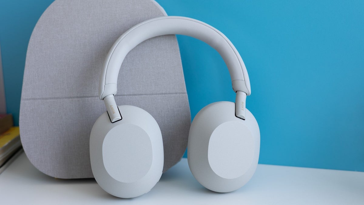 Sony WH-1000XM5 on a white table against a blue background.
