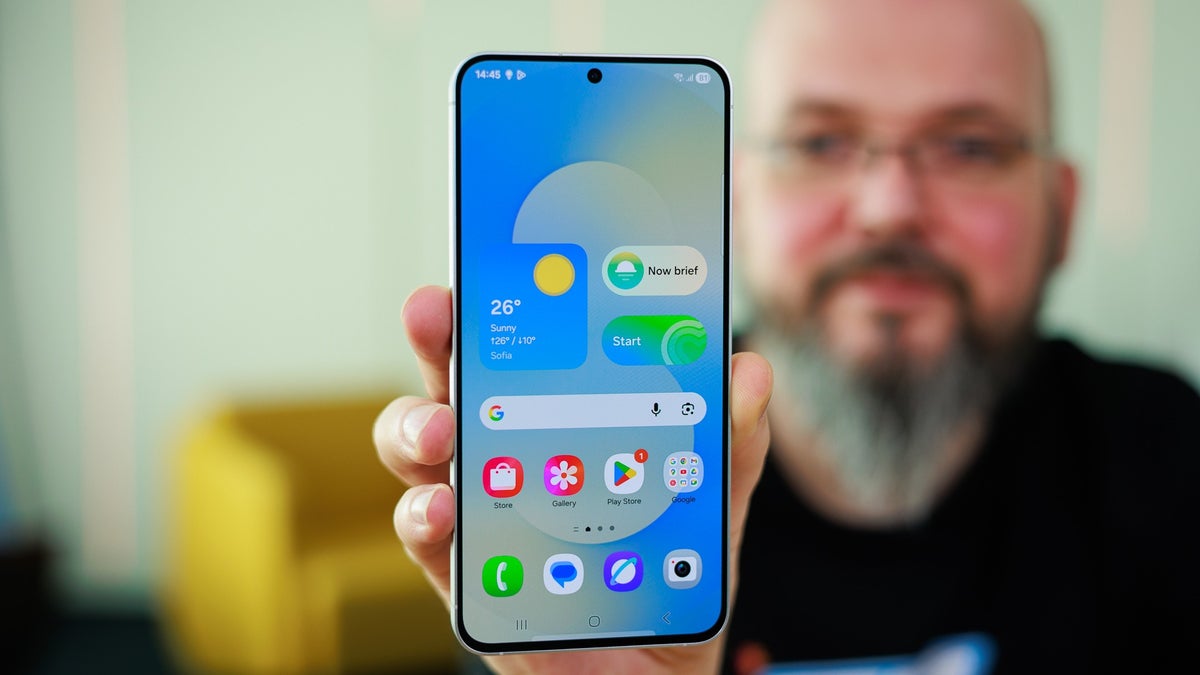 Close-up of the Galaxy S25 FE being held by a person visible in the background.