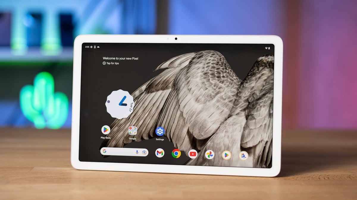 Google Pixel Tablet on a wooden table, with an owl wing displayed on its touchscreen.