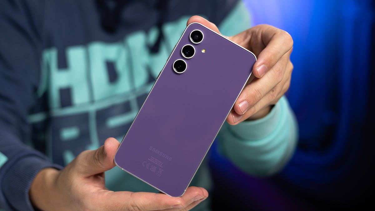 A man holding a Galaxy S23 FE in his hands, showing the back of the phone to the camera.