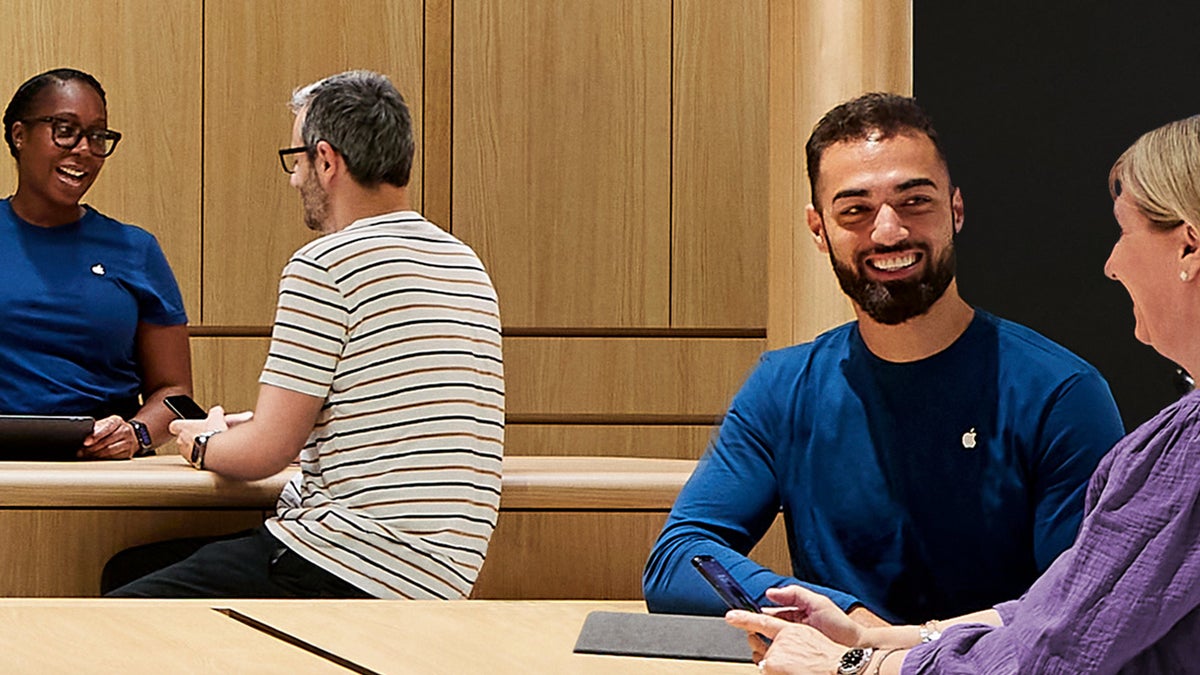 Dua teknisi Genius Bar membantu pelanggan di Apple Store