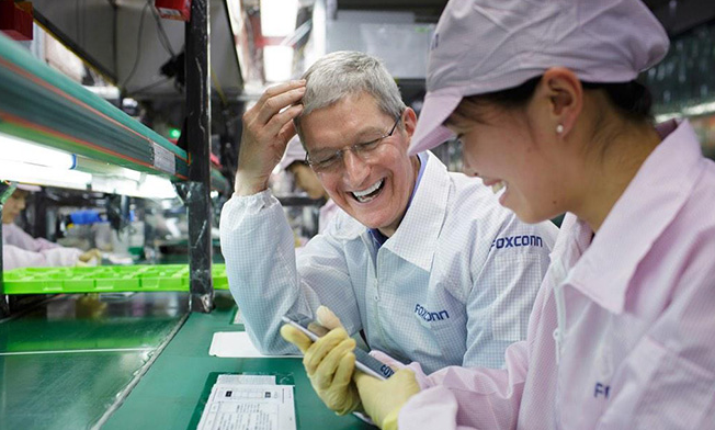Apple CEO Tim Cook watches on as a Foxconn employee puts the finishing touches on an Apple iPhone 6 being built at a Foxconn factory - Tim Cook visits a Foxconn factory where the Apple iPhone 6 is built