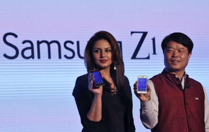Samsung India president Hyun Chil Hong (R) shows off the Tizen powered Samsung Z1 along with Bollywood actress Huma Qureshi - Tizen powered Samsung Z1 handset off to a slow start in India