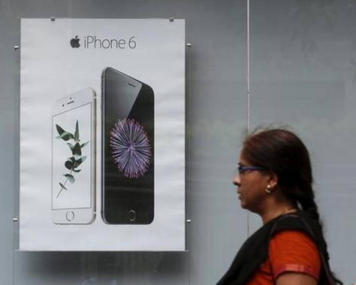 A consumer walks past an Indian electronics store hawking the Apple iPhone 6 in 2015 - Any Apple Store open in India must have 30% of its inventory locally sourced?