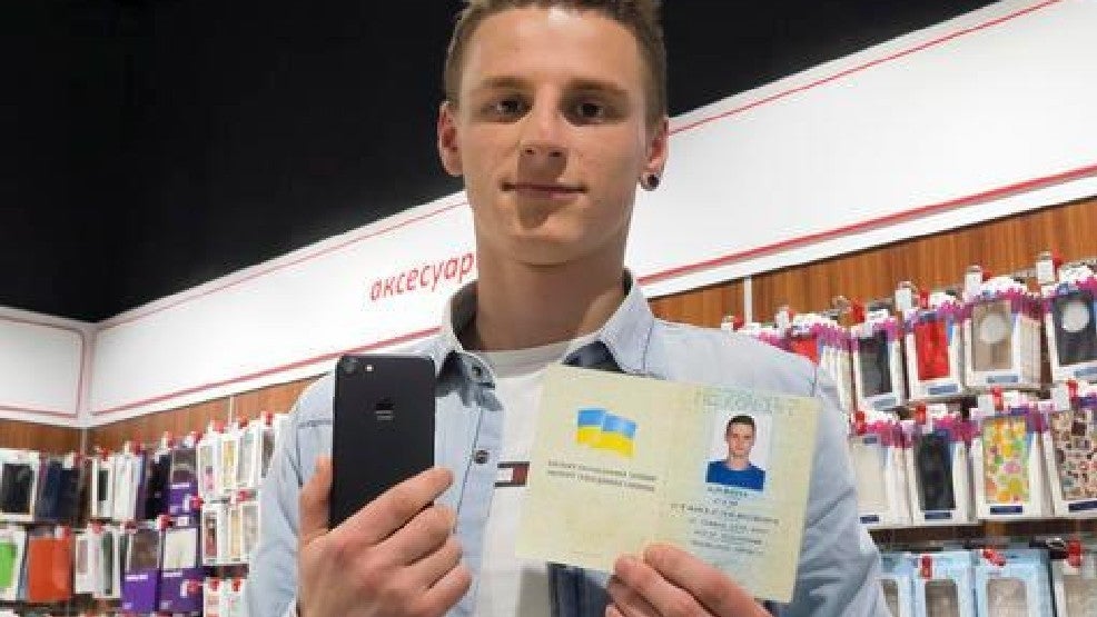 The former Olexander Turin holds his new iPhone 7 in his right hand and his passport in the left; Turin changed his name legally to iPhone 7 to win the phone - Man changes his name to "iPhone 7" so that he can win one