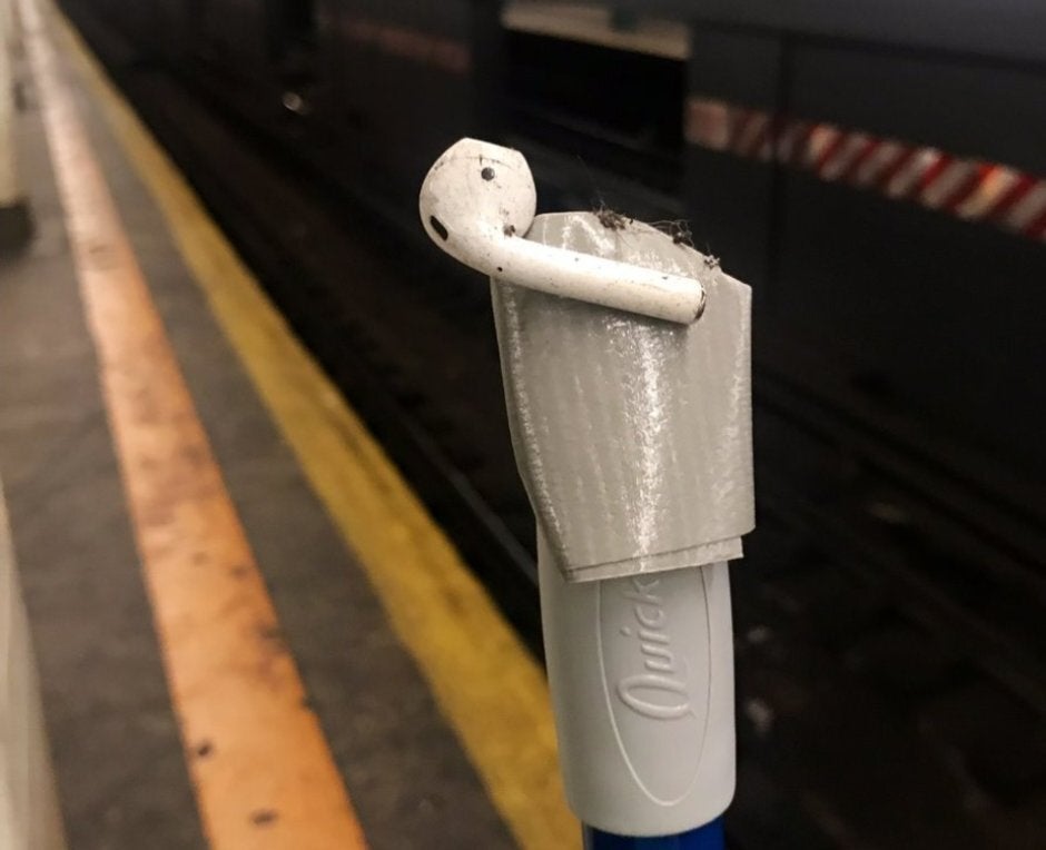 A broom handle and duct tape is used to save the AirPod that was laying near a subway rail - Lost AirPods are becoming a problem in New York City