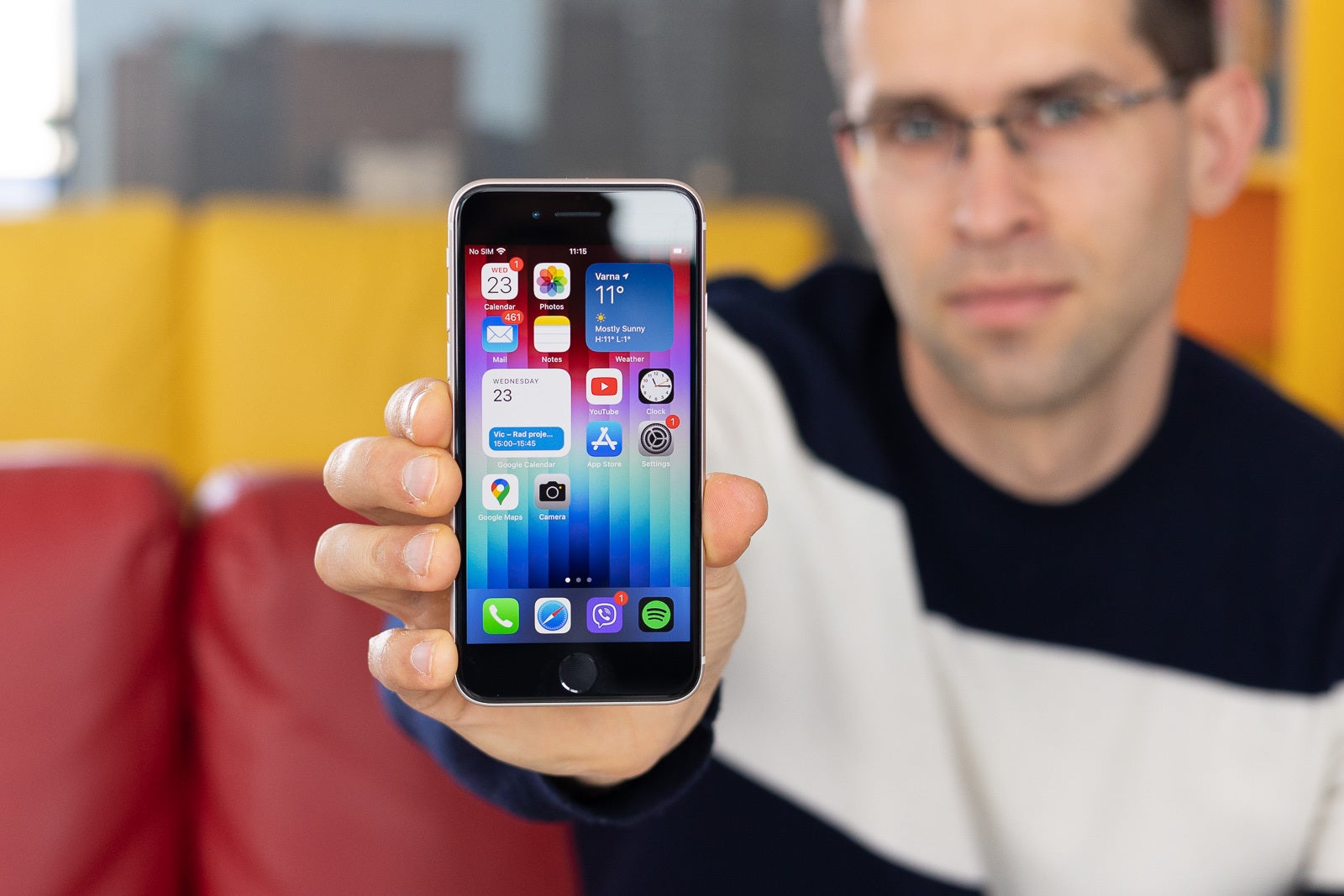 iPhone SE held by presenter with its screen towards the camera. The phone is on, homescreen is visible