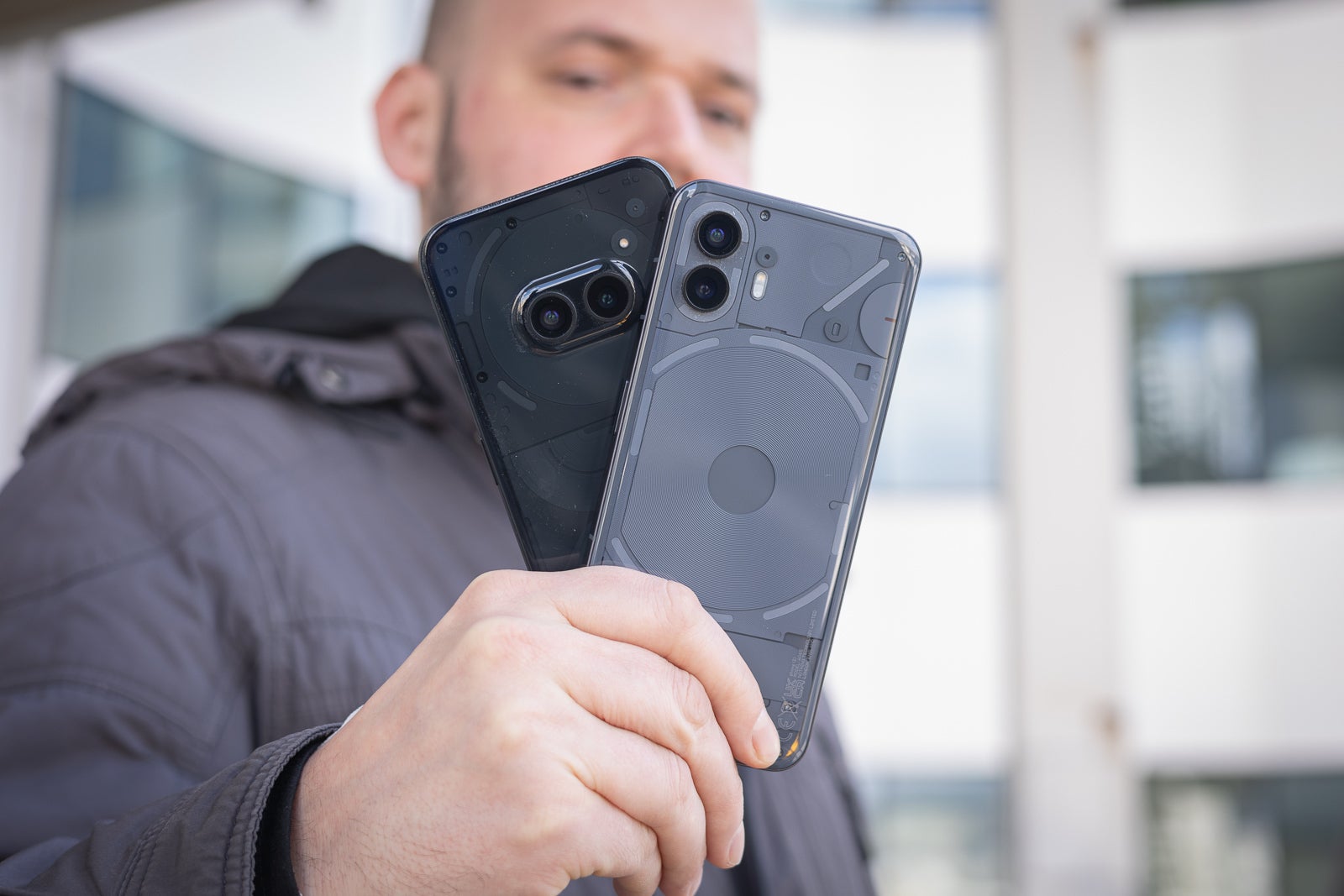 Image of a person holding a Nothing Phone (2) and Nothing Phone (2a)